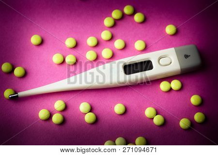 Small Medical Pharmacetic Round Pills, Vitamins, Drugs And Electronic Digital Thermometer On A Pink 