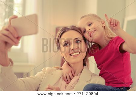 Happy Positive Mom And Daughter Taking Selfies Together