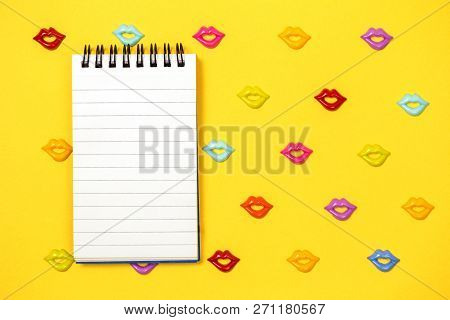 Joyful Pattern Of Colorful Lips On Yellow Background With A Small Rooled Notepad On Top, Copy Space 