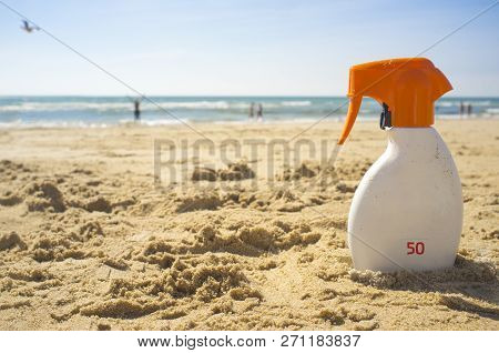 Sunblock Cream With Sun Protection Factor Or Spf 50 On Beach Sand. People On Background