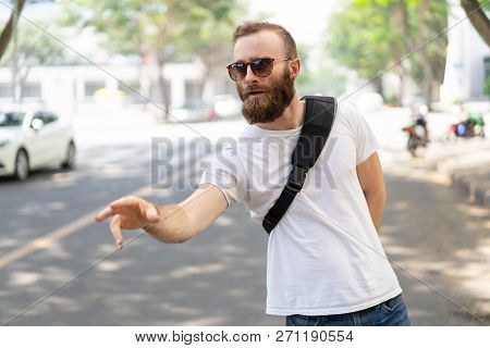 Concerned Tourist Calling Taxi. Bearded Young Man In Sunglasses And Summer Shirt Standing On Road An