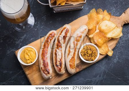 Grilled german sausages with mustard and fried potato chips