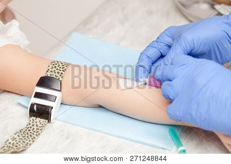 Doctor or nurse ready to take a blood sample from little girl's arm vein with a vacutainer. Pediatric venipuncture or venepuncture procedure
