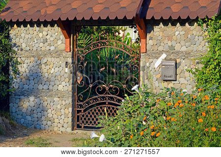 Wrought Iron Gate In A Stone Fence Under The Iron Canopy
