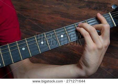 Hand Of Man Playing Six-string Guitar On Wooden Background. Template For Concert Poster