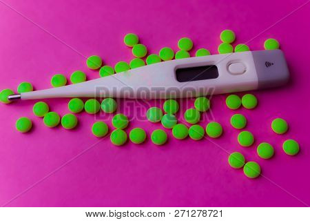 Small Medical Pharmacetic Round Pills, Vitamins, Drugs And Electronic Digital Thermometer On A Pink 