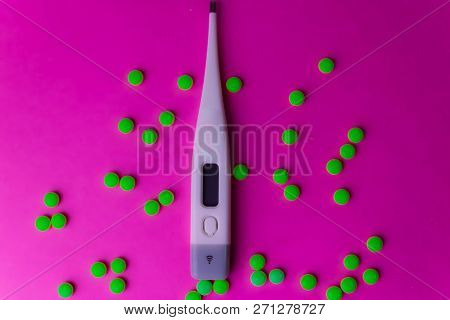 Small Medical Pharmacetic Round Pills, Vitamins, Drugs And Electronic Digital Thermometer On A Pink 