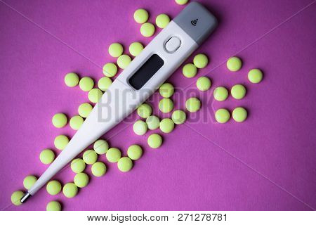 Small Medical Pharmacetic Round Pills, Vitamins, Drugs And Electronic Digital Thermometer On A Pink 