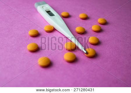 Small Medical Pharmacetic Round Pills, Vitamins, Drugs And Electronic Digital Thermometer On A Pink 