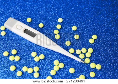 Small Medical Pharmacetic Round Tablets, Vitamins, Drugs And Electronic Digital Thermometer On A Blu