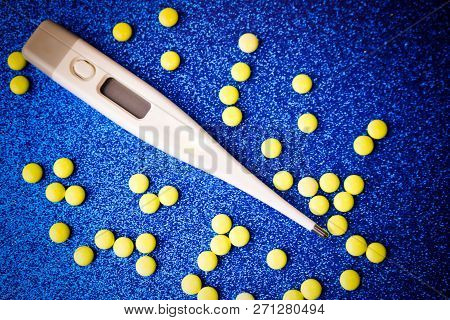 Small Medical Pharmacetic Round Tablets, Vitamins, Drugs And Electronic Digital Thermometer On A Blu