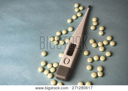 Small Medical Pharmacetic Round Tablets, Vitamins, Drugs And Electronic Digital Thermometer On A Blu