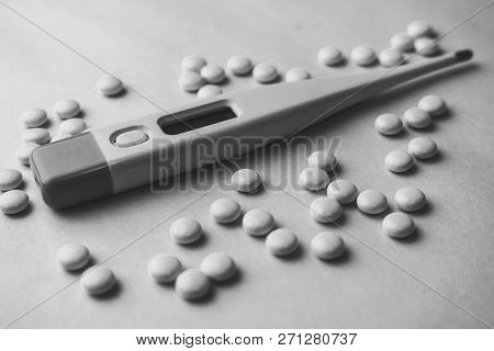 Small Medical Pharmaceptic Round Pills, Vitamins, Drugs And Electronic Digital Thermometer On A Blac