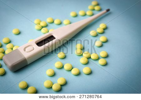 Small Medical Pharmacetic Round Tablets, Vitamins, Drugs And Electronic Digital Thermometer On A Blu