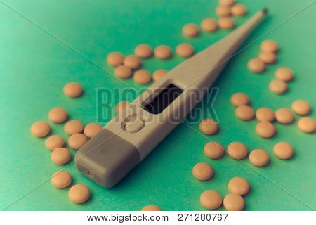 Small Medical Pharmacetic Round Tablets, Vitamins, Drugs And Electronic Digital Thermometer On A Gre