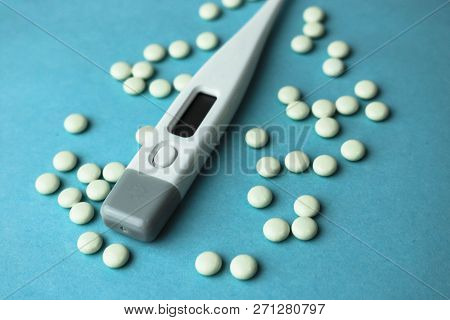 Small Medical Pharmacetic Round Tablets, Vitamins, Drugs And Electronic Digital Thermometer On A Blu