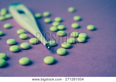 Small Medical Pharmacetic Round Pills, Vitamins, Drugs And Electronic Digital Thermometer On A Pink 