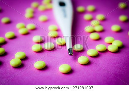 Small Medical Pharmacetic Round Pills, Vitamins, Drugs And Electronic Digital Thermometer On A Pink 