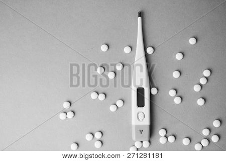 Small Medical Pharmaceptic Round Pills, Vitamins, Drugs And Electronic Digital Thermometer On A Blac