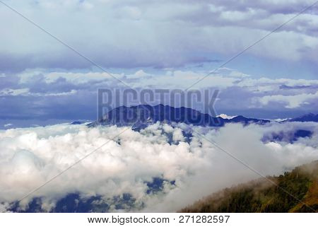 Landscape - View From The Mountain Pass On A Sunny Day To The Valley Hidden By Low Clouds