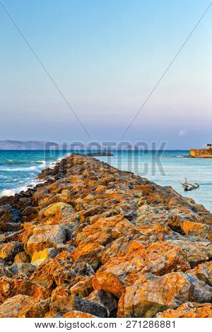Long Stony Spit Going Far To Sea In Heraklion City On Crete, Greece. Roaring Waves Batter Against Th