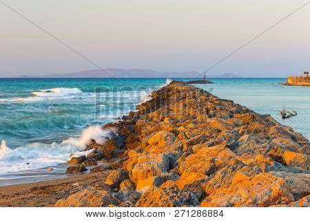 Long Stony Spit Going Far To Sea In Heraklion City On Crete, Greece. Roaring Waves Batter Against Th