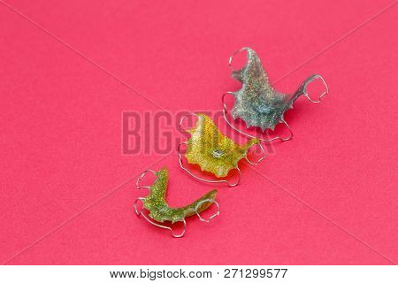 Colorful Dental Braces Or Retainers For Teeth On Pink Background, Closeup