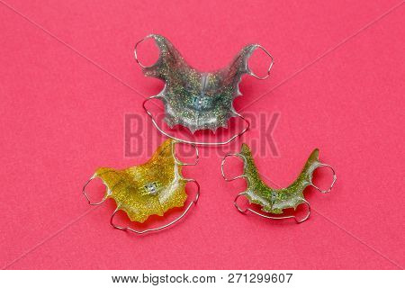 Colorful Dental Braces Or Retainers For Teeth On Pink Background, Closeup