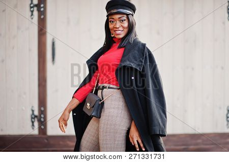 African American Fashion Girl In Coat And Newsboy Cap Posed At Street.