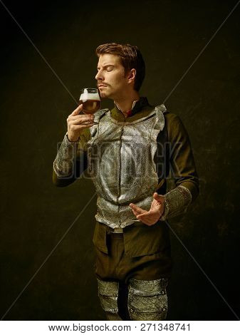 Medieval Knight With Beer On Dark Studio Background. Portrait In Low Key Of Brutal Man In Tradishion