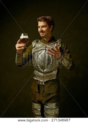 Medieval Smiling Happy Knight With Beer On Dark Studio Background. Portrait In Low Key Of Brutal Man