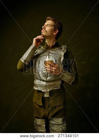 Medieval Knight With Beer On Dark Studio Background. Portrait In Low Key Of Brutal Man In Tradishion