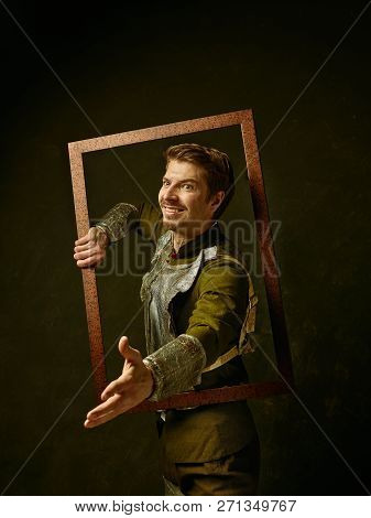 Medieval Knight On Dark Studio Background. Portrait In Low Key Of Brutal Man In Tradishional Retro C