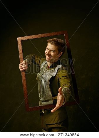 Medieval Knight On Dark Studio Background. Portrait In Low Key Of Brutal Man In Tradishional Retro C