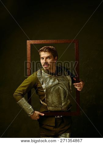Medieval Knight On Dark Studio Background. Portrait In Low Key Of Brutal Man In Tradishional Retro C