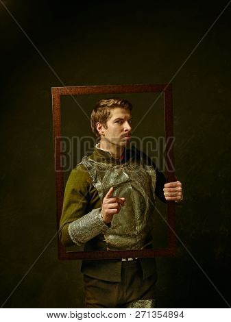 Medieval Knight On Dark Studio Background. Portrait In Low Key Of Brutal Man In Tradishional Retro C