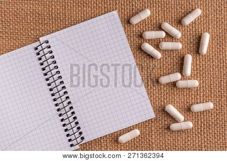 Medical Capsules And Pills Around A Blank Notepad On A Wicker Background, Close-up, Top View, With C