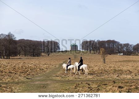 Klampenborg, Denmark - March 25, 2017:  Two Horse Riders In Front Of The Small Castle Inside The Dee