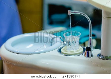 Plastic Glass With Water For Dentist Common Operation Of Cleaning Mouth.