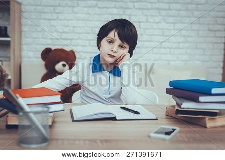 Child Is Doing Homework. Child Is A Little Black Haired Boy. Boy Is Upset. Child Sitting At Table. B
