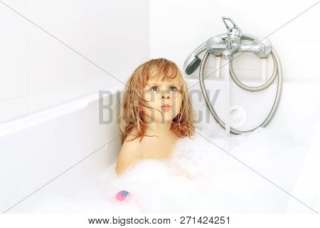 Serious Blue-eyed Toddler In The White Bath. Infant Washing And Bathing. Hygiene And Health Care. Li