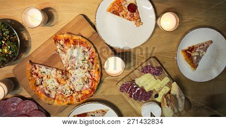 Table With Various Food Served With Red Wine And Candles