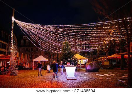 Strasbourg, France - Nov 29, 2017: People Gathering Under Large Multicolored Garland In Place Du Mar
