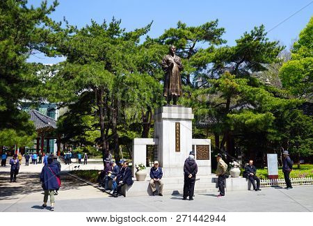 Seoul, South Korea - April 2018:  Older men rest in the park. Statue of famous Korean poet Khan Young Un. Tapgol Park.