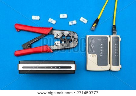 Cripmer Tool, Network Cable Tester And A Switch Router Isolated On The Blue Background. Network Mait