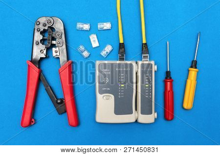 Cripmer Tool, Network Cable Tester And Screwdrivers Isolated On The Blue Background. Network Maitena