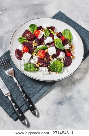 Dish With A Salad Of Feta, Beetroot, Cherry Tomatoes And Walnuts On A Concrete Background