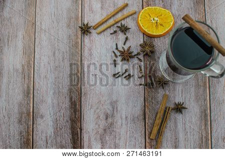 Hot Mulled Wine Drink With Lemon, Apple, Cinnamon, Anise And Other Spices In A Glass Cup Between Fir