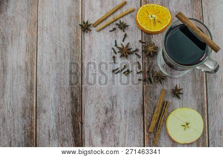Hot Mulled Wine Drink With Lemon, Apple, Cinnamon, Anise And Other Spices In A Glass Cup Between Fir