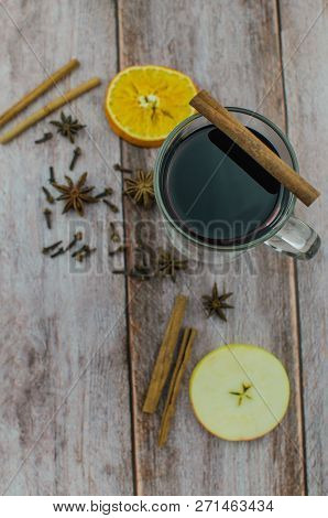 Hot Mulled Wine Drink With Lemon, Apple, Cinnamon, Anise And Other Spices In A Glass Cup Between Fir
